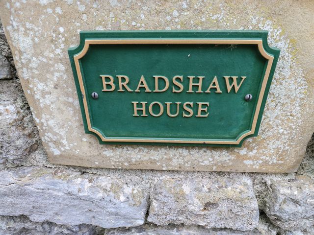 A plaque displaying the name Bradshaw House on a stone wall in Hope Valley