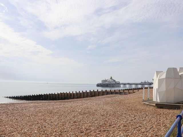 View of a pier and beach with a geometric cabin at Pebbles Eastbourne
