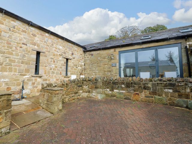 An outdoor area with a stone wall and windows at The Holt Barn in Kirkby Malzeard