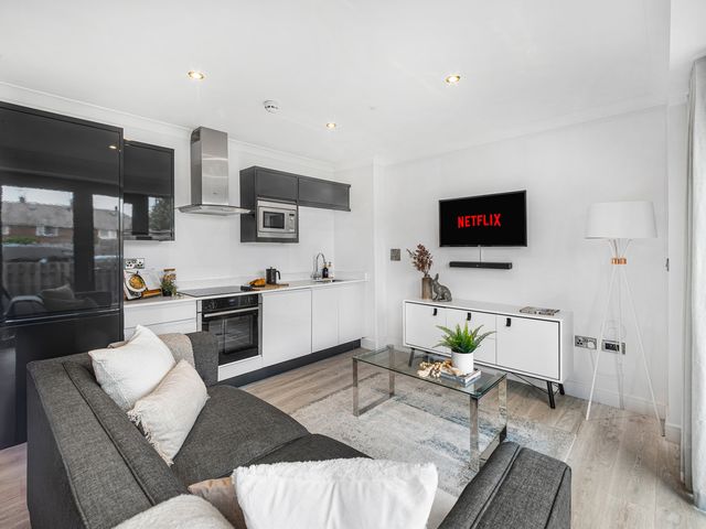 A living room with a sofa and kitchen appliances at York Suite in Chester