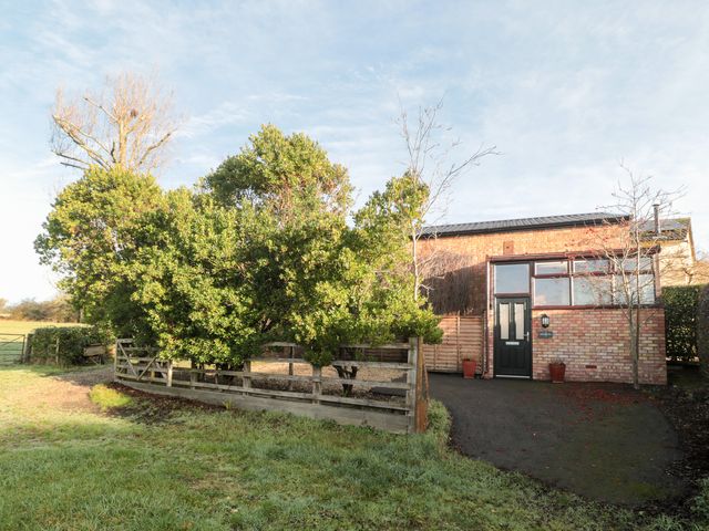 An exterior view of a house surrounded by trees and a fence at Wellinghill Cottage at Wellinghill House Charlton Kings