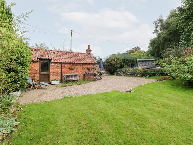 A garden with a cottage, benches, and table at The Retreat in Norwich
