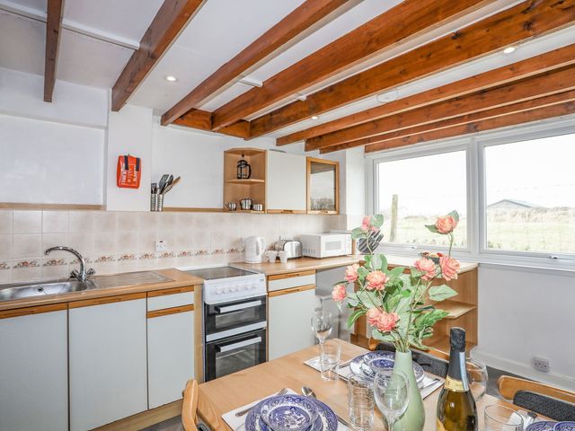 A kitchen with a dining table and appliances at Cilan - 2 Ty'n Don Llanengan near Abersoch