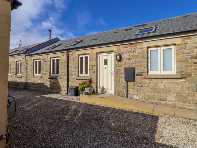 An outdoor view of a stone building with a door and windows at Hideaway Cottage No 1 Seahouses