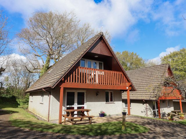 A house with a balcony and outdoor seating area at Mayfly Lodge, St Tudy