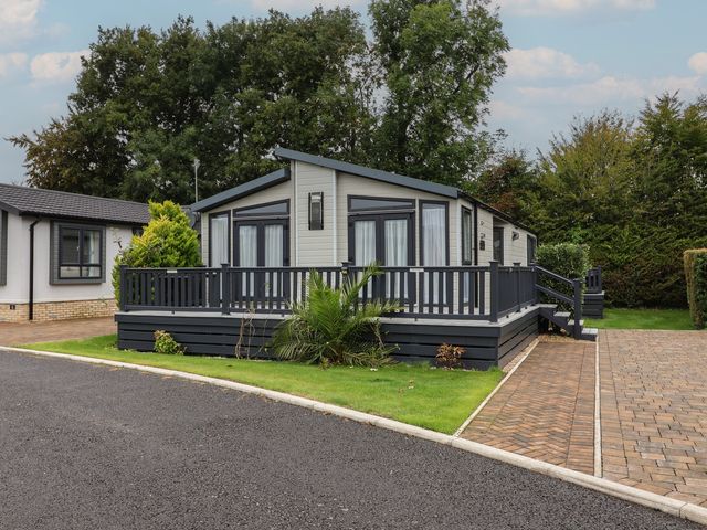 A mobile home with a deck and palm tree at Whistler in Wimborne