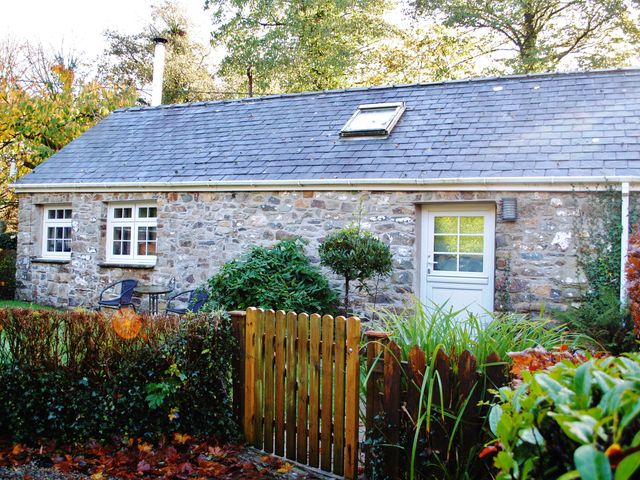 A stone cottage with a fenced yard and chairs at Corner Cottage in Maenclochog