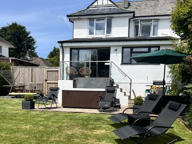 A garden with a hot tub and seating area at Newlands in Yelverton