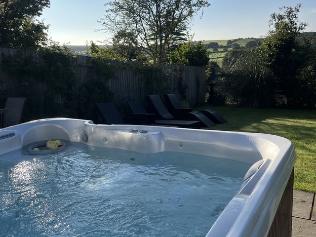 A hot tub and deck chairs in a garden at Newlands in Yelverton