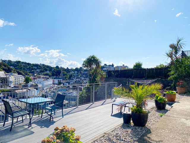 A garden with a table and chairs overlooking a view at Ockendon House Apartment B in Torquay