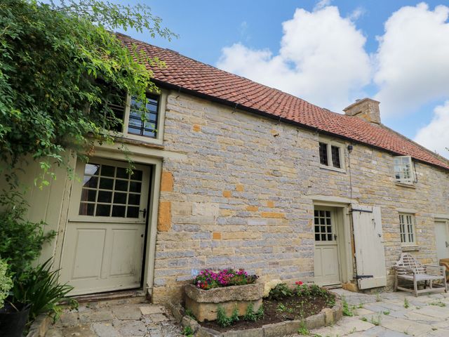 An outdoor area with a stone wall and plants at The Farmhouse in Langport