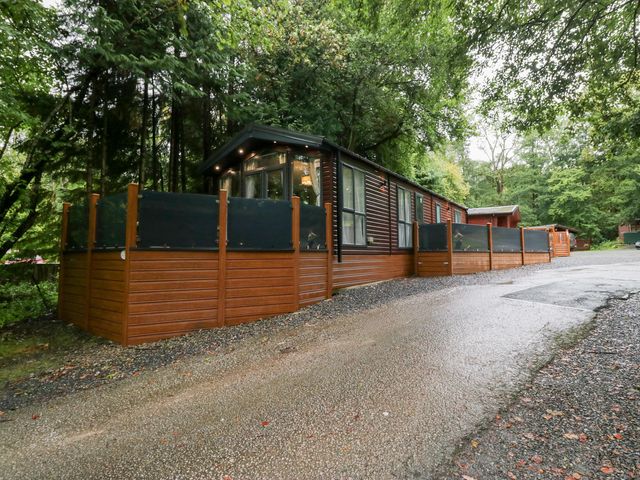 A log cabin with fencing and trees at Feather Hill Lodge in Windermere