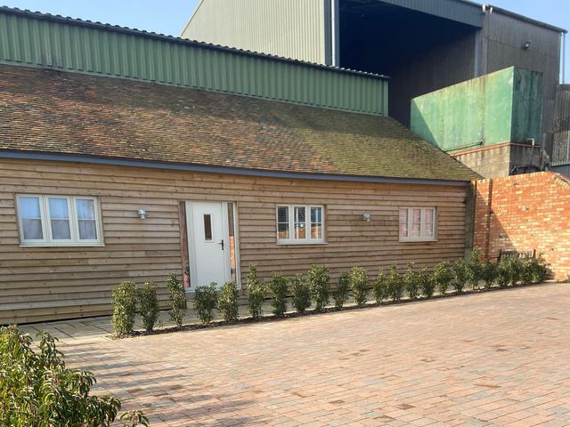 A wooden building with windows and door at The Cart Shed in Bedford