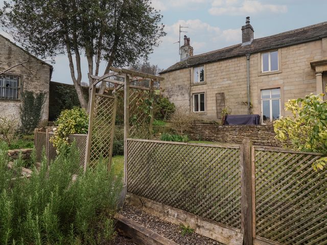 A garden scene with a tree and fence at Wood End Farm Cottage