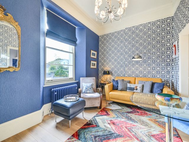 A living room with a yellow sofa and a coffee table at Muntham Apartment 4 in Torquay