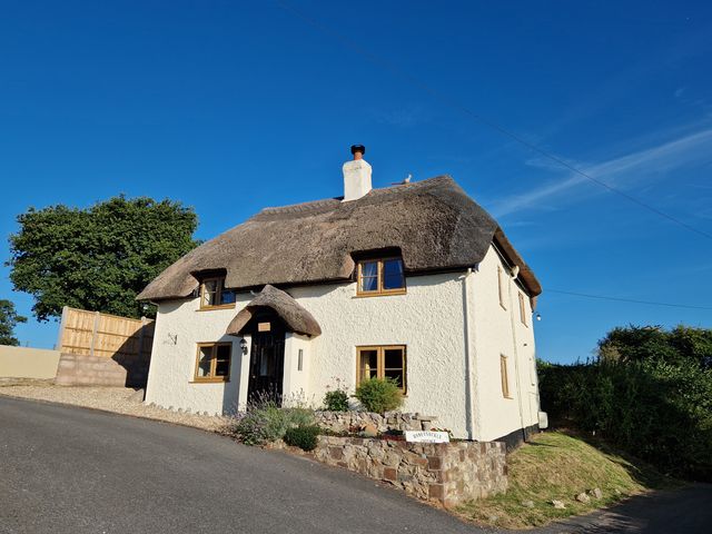 A thatched roof house located at Honeysuckle Cottage in Smallridge