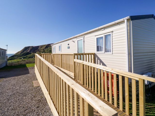 A caravan with a wooden deck overlooking the coast at Guillemot St Bees