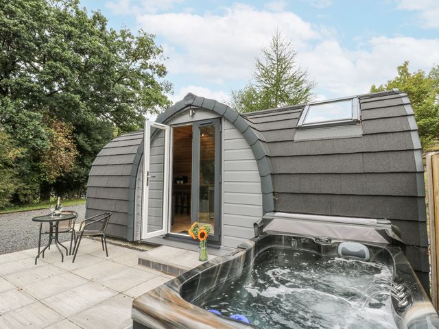 A hot tub and seating area outside a modern structure at Oak View in Rhayader
