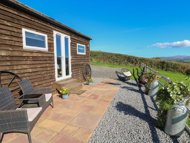 An outdoor area with a cabin, chairs and flower pots at Sychnant Farm Retreat in Llanedi near Pontarddulais