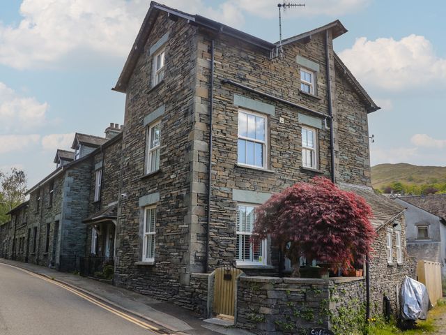 A stone house with windows and a tree at Park View Studio in Ambleside