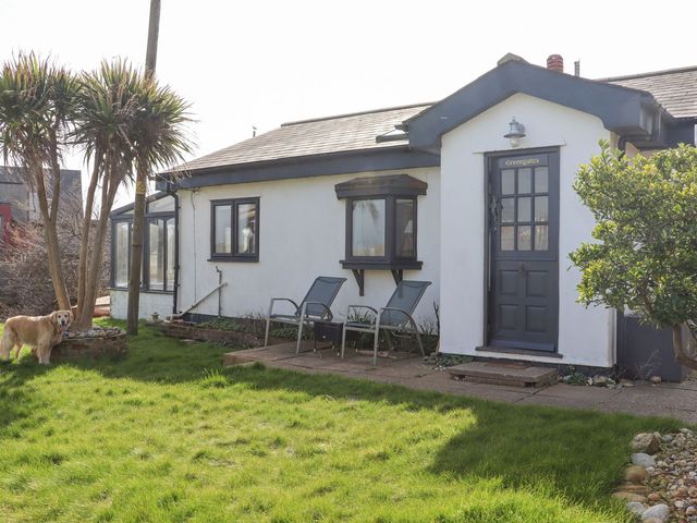 An outdoor view of a house with chairs and a dog at Greengates in Rye
