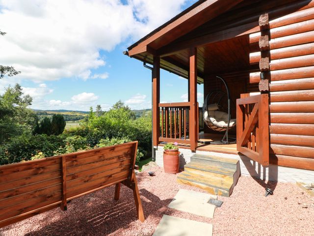 An outdoor area with a log cabin, steps, a hanging chair, and a bench at Deer’s Leap