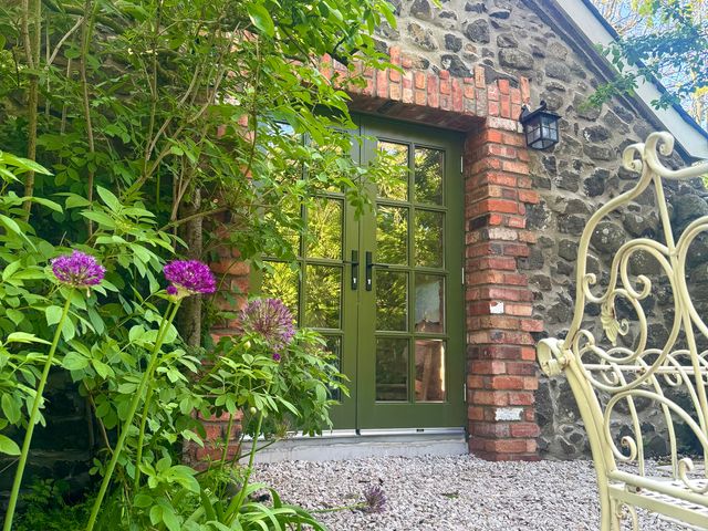 A door with a green frame surrounded by plants at Auld Cider Makers Cottage in Portstewart, County Londonderry