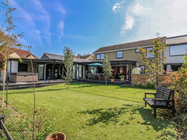 A garden with a house, hot tub, and bench at Manor Farm House in Merton near Bicester