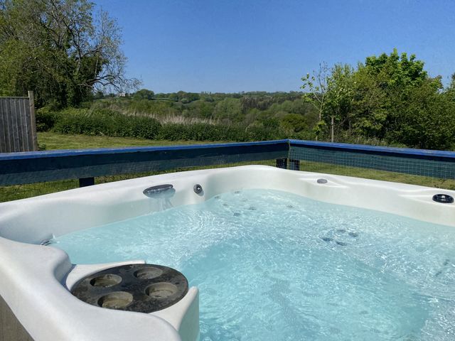A hot tub with water and trees in the background at The Cow Shed in Bishopswood