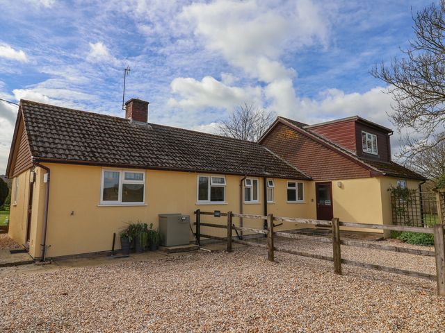 A house with a gravel driveway and fence at Court House Farmhouse in Charmouth