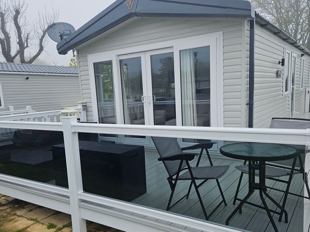 A cabin with a deck area featuring a table and chairs at Primrose Valley Holiday Park - Holiday Accommodation 10790, Filey