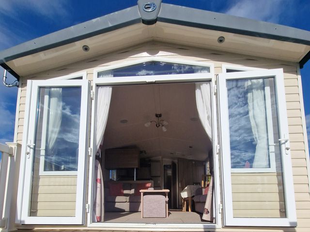 A living room with a sofa and table visible through open doors at The Crest, Filey (private land) - Holiday Accommodation 11967, Filey