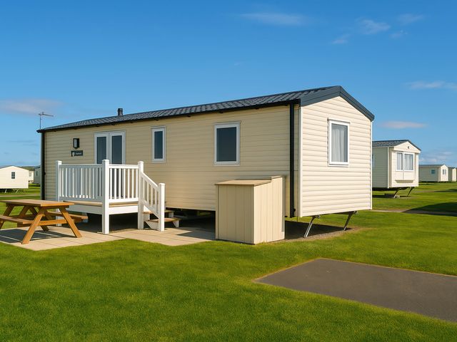 A mobile home with a deck and table at Littlesea Holiday Park - Holiday Accommodation 13127 Weymouth