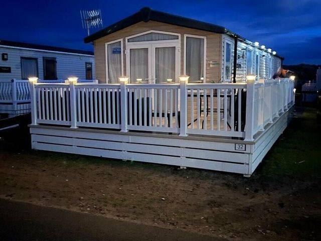 a holiday caravan with a deck and lights at Greenacres Holiday Park - Holiday Accommodation 13413 in Porthmadog