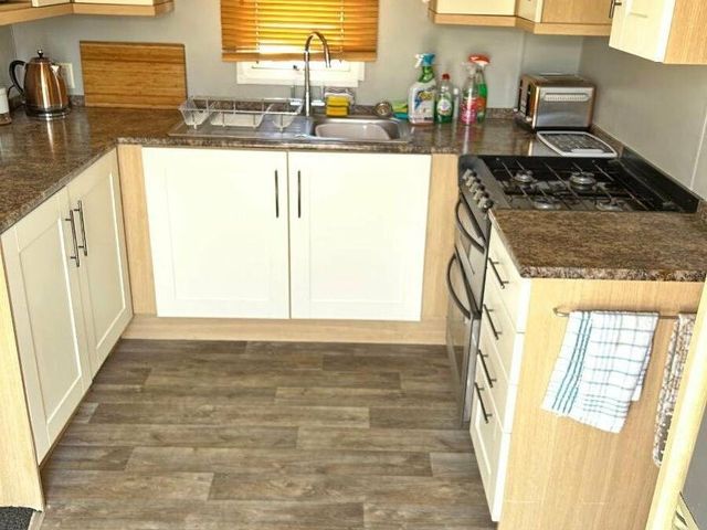a kitchen with wooden cabinets and a sink at Golden Gate Holiday Centre - Holiday Accommodation 14646, Towyn