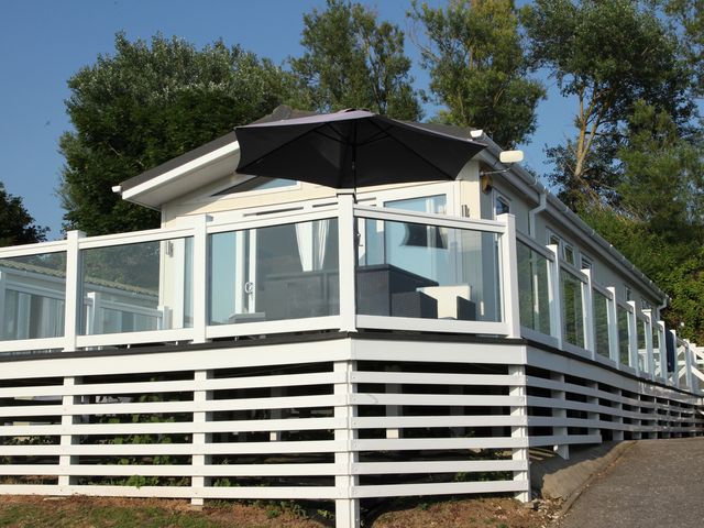 A building with a deck and umbrella at Waterside Bowleaze Cove Holiday Park - Holiday Accommodation 16929 in Weymouth
