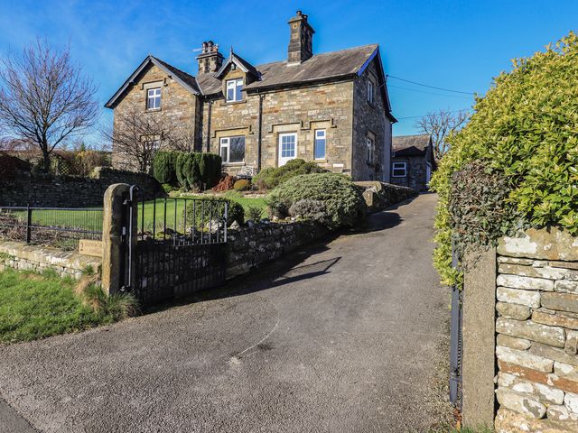An outdoor view of a house with a garden and a driveway at 2 Lupton Hall Cottages in Carnforth