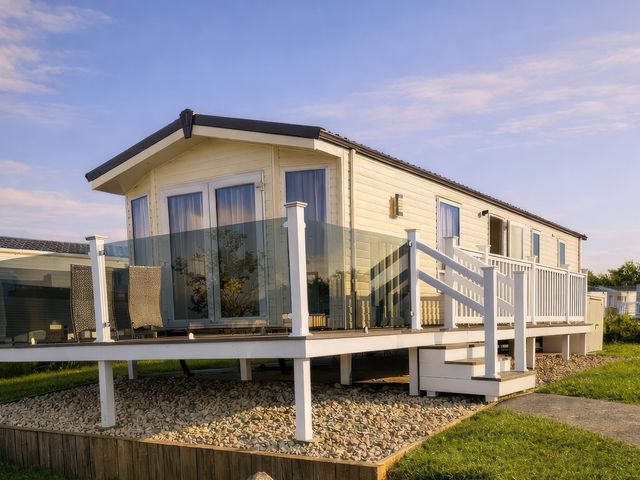 A holiday home with deck and glass railing at Primrose Valley Holiday Park - Holiday Accommodation 20012, Filey