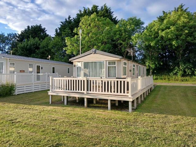 a holiday home with a wooden deck surrounded by grass at Hoburne Cotswolds - Holiday Accommodation 20158 South Cerney