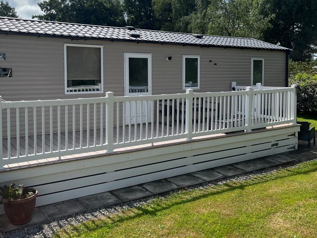 A mobile home with a deck and railing at Hafan y Mor Haven - Holiday Accommodation 20548 Pwllheli