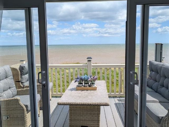 a seating area overlooking the sea with a table and chairs at Skipsea Sands Holiday Park - Holiday Accommodation 20902 in Skipsea, Driffield