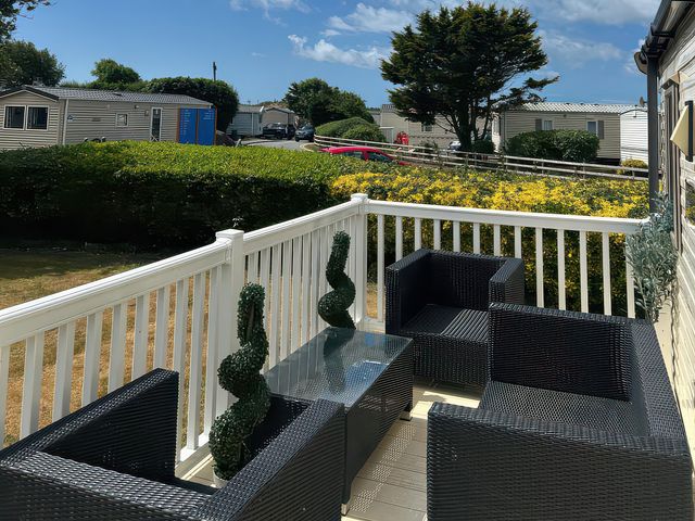 A terrace with black outdoor seating and a glass table at Greenacres Holiday Park - Holiday Accommodation 21168 Porthmadog