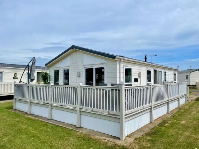 A holiday cabin with decking and outdoor furniture at Manor Park Holiday Village - Holiday Accommodation 22030 Hunstanton