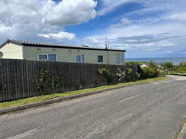 A caravan with flowers beside a fence at Newlands (private land) - Holiday Accommodation 22269 Filey