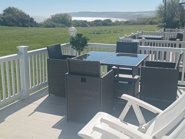 A terrace with chairs and a table overlooking a lawn at Primrose Valley Holiday Park - Holiday Accommodation 2533, Filey