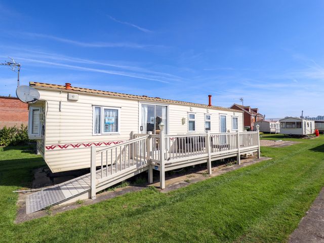 A caravan with decking and satellite dish at Coastfield Holiday Village - Holiday Accommodation 2604 Ingoldmells