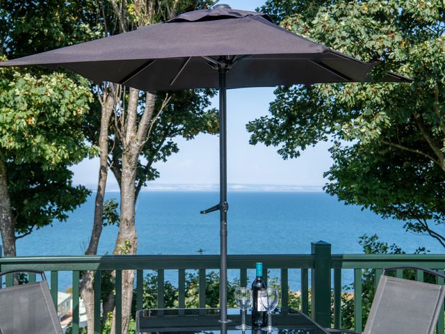 An outdoor space with a table and umbrella overlooking the ocean at St Andrews Holiday Park - Holiday Accommodation 2944 St Andrews