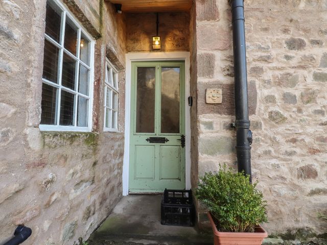 An entrance with a green front door and stone wall at The Snug in Morecambe