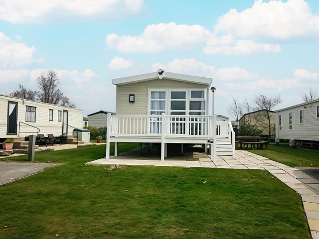 An outdoor view of a mobile home with a deck at Hopton Holiday Village - Holiday Accommodation 632 Great Yarmouth