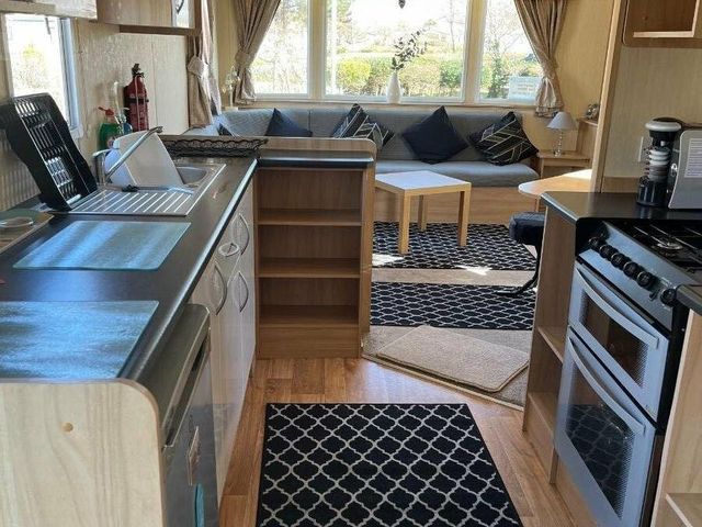 a kitchen and living area with a sofa and table at Greenacres Holiday Park - Holiday Accommodation 89, Porthmadog